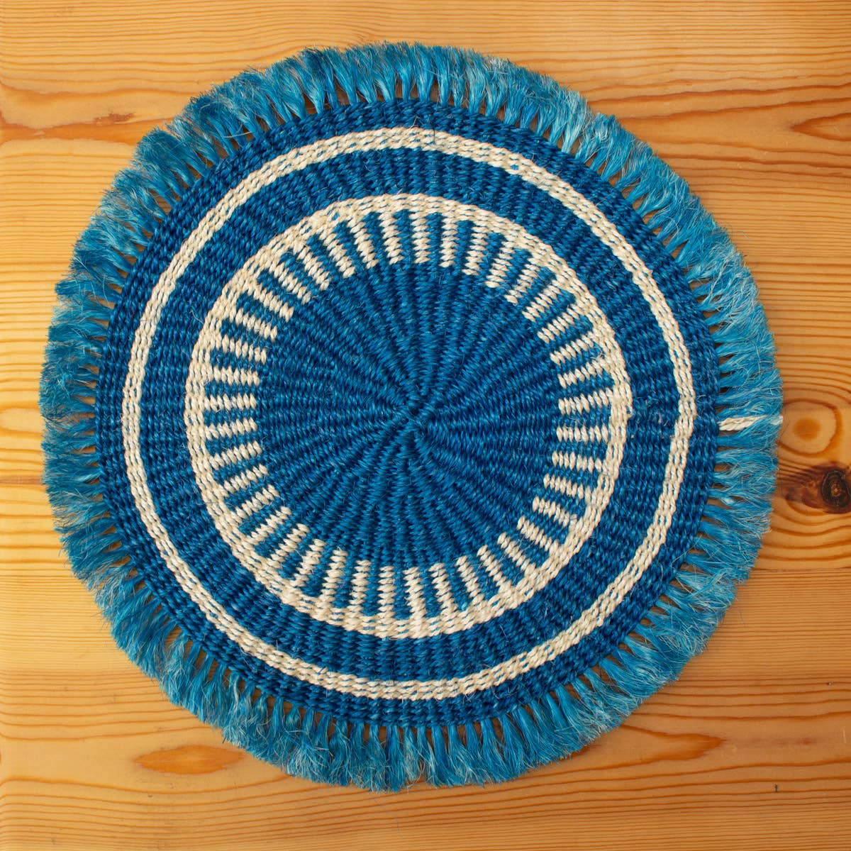 Blue and white woven placemat on a wooden surface