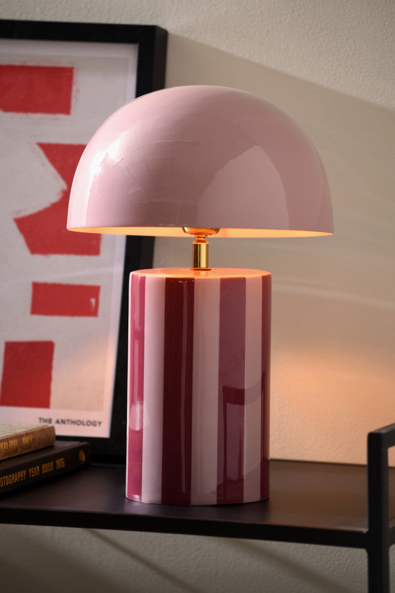 Pink table lamp on a shelf with a framed picture in the background