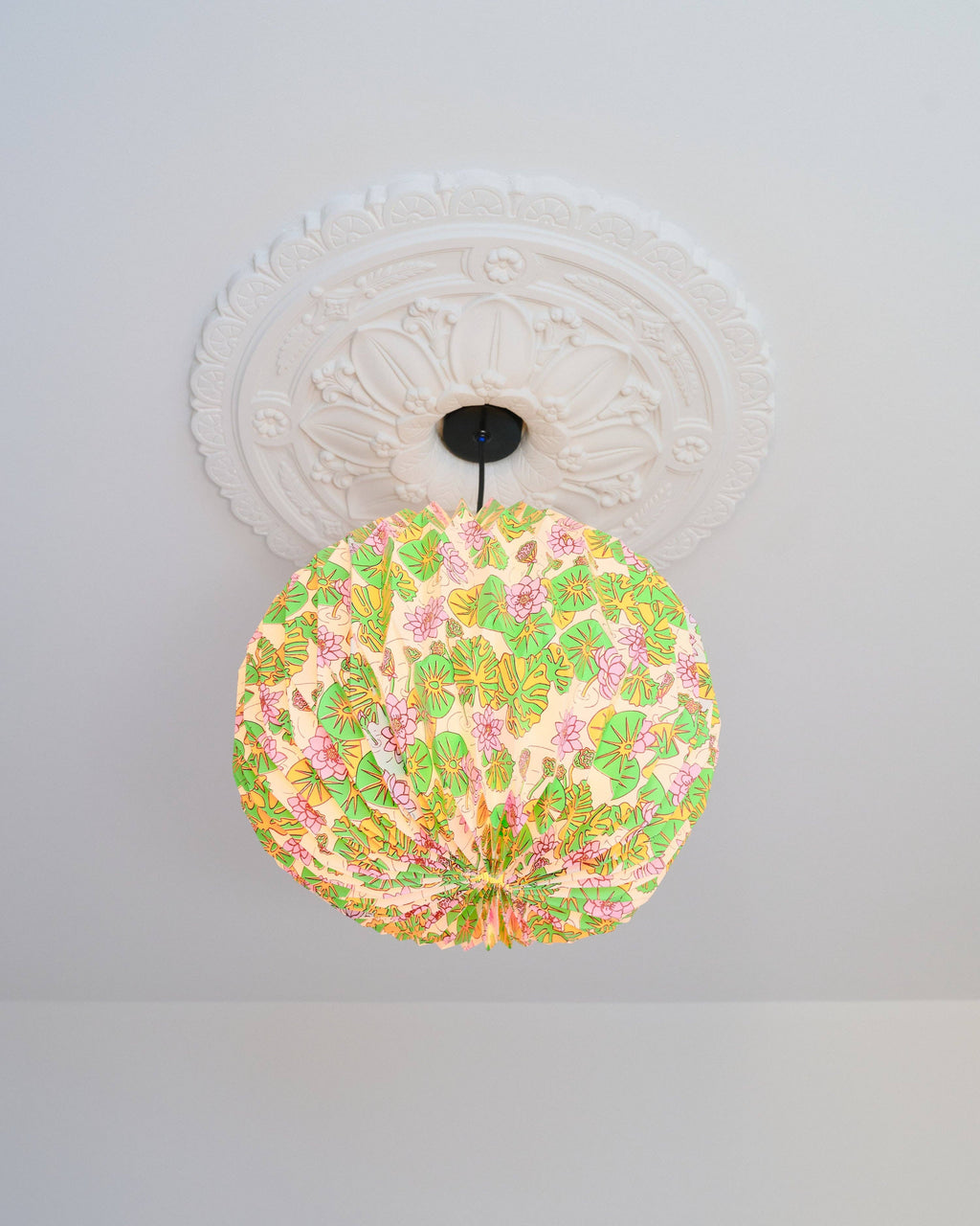 Decorative ceiling light fixture with floral pattern on a white ceiling.