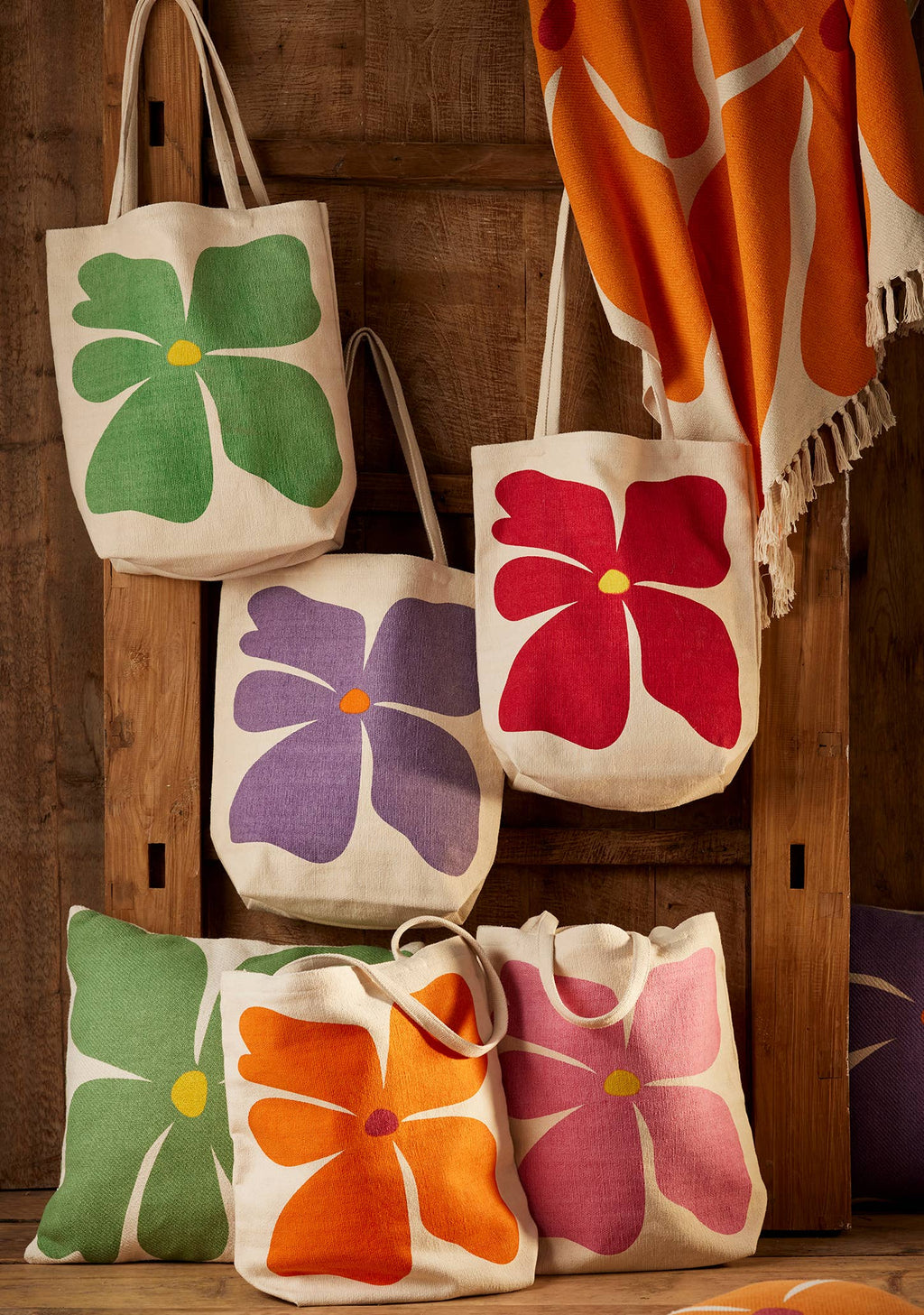 Set of floral-patterned tote bags on a wooden surface with a blanket in the background.