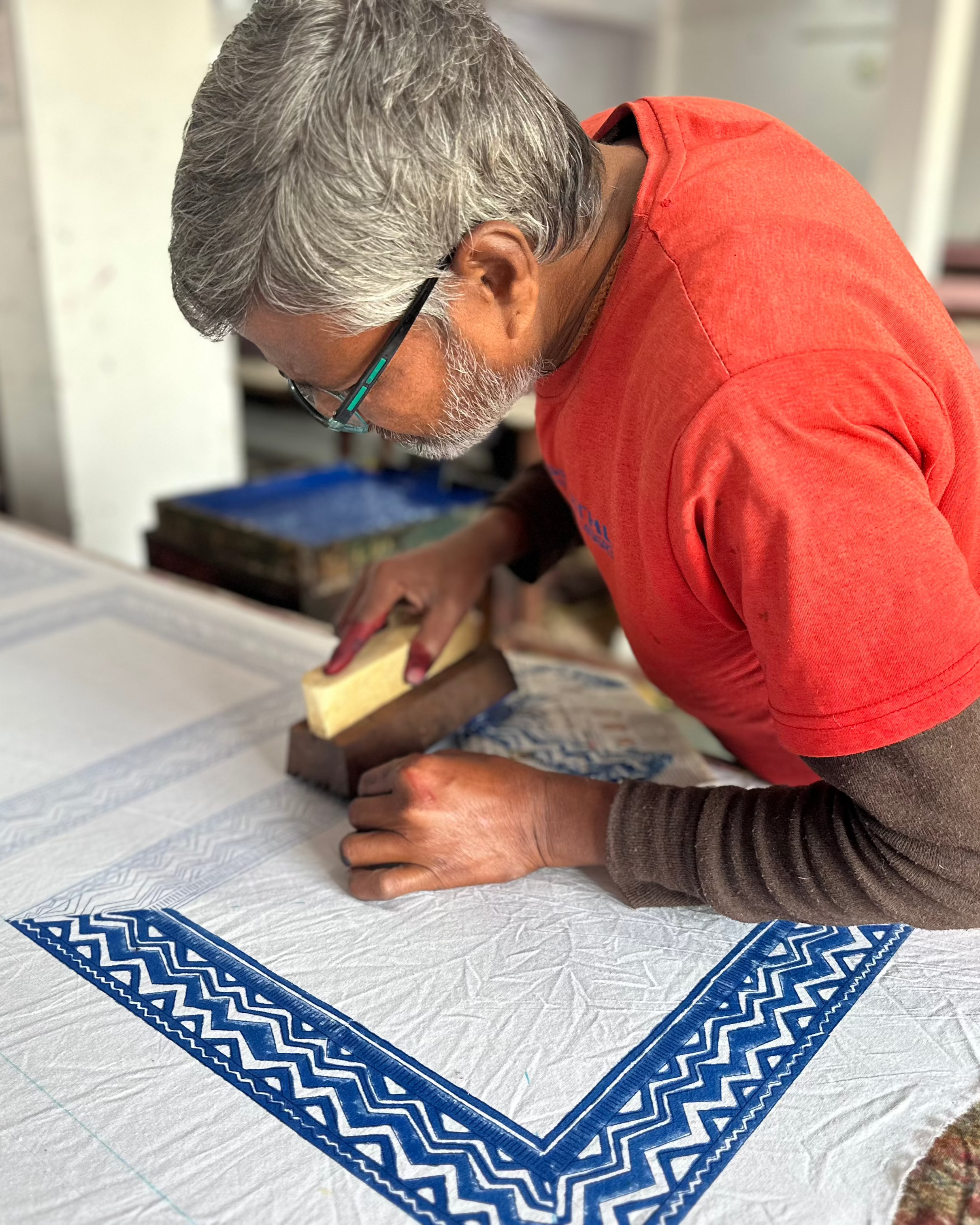 Person in a red shirt working on a craft project with blue and white patterns