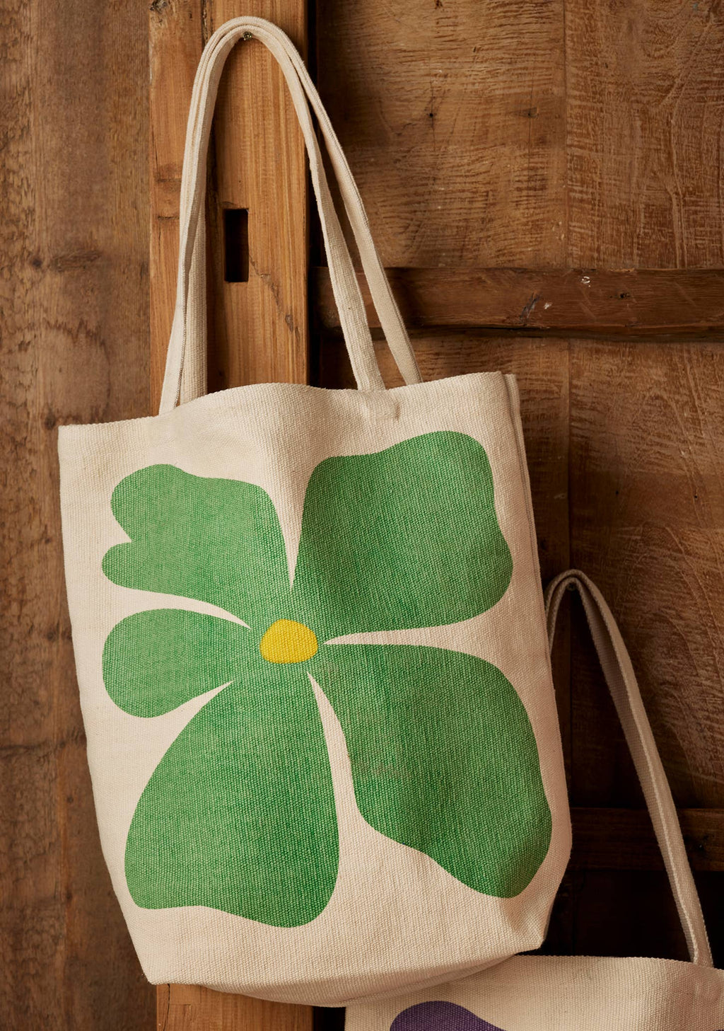 Tote bag with a green clover design on a wooden surface