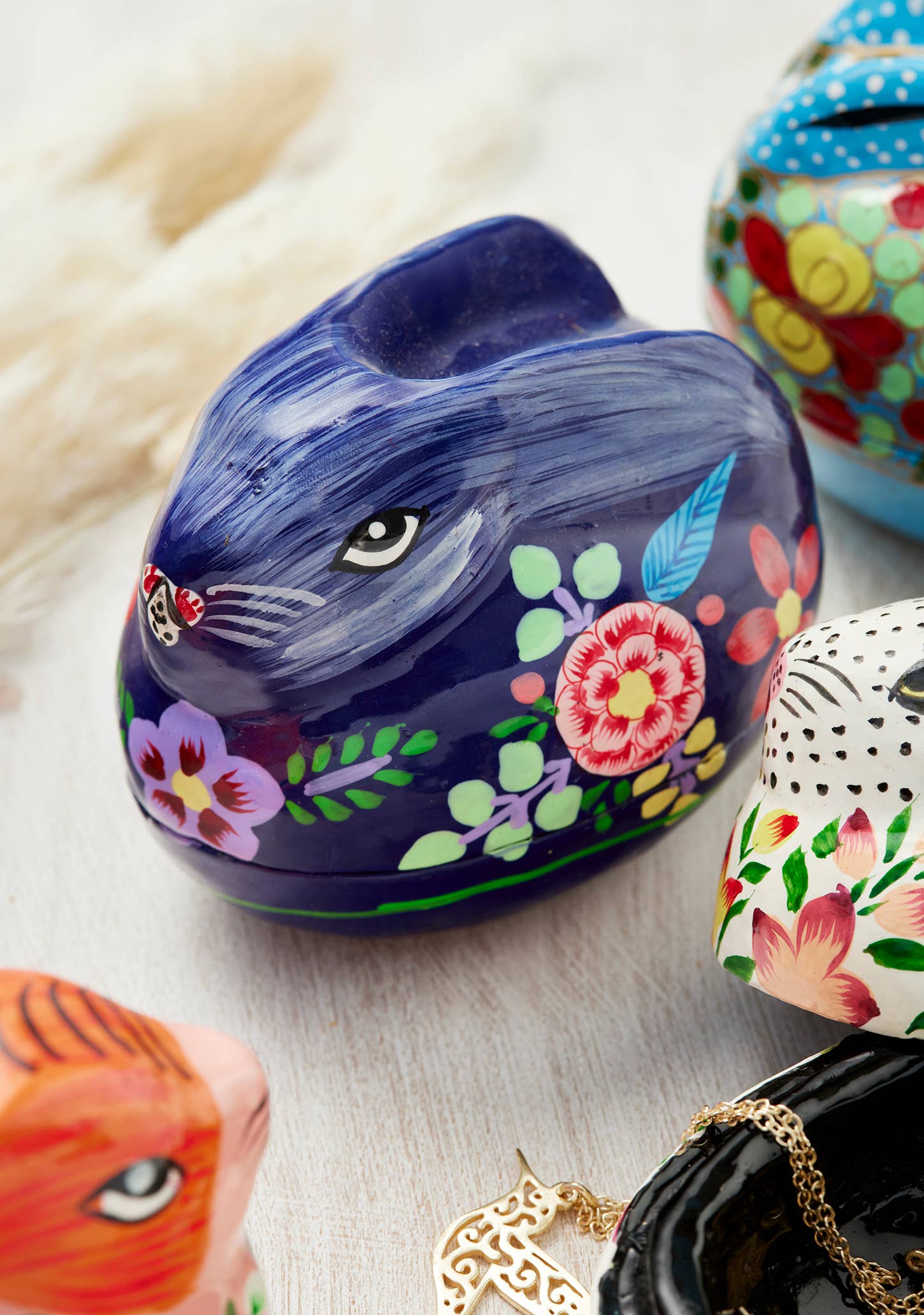 Decorative rabbit-shaped container with floral designs on a light wooden surface.