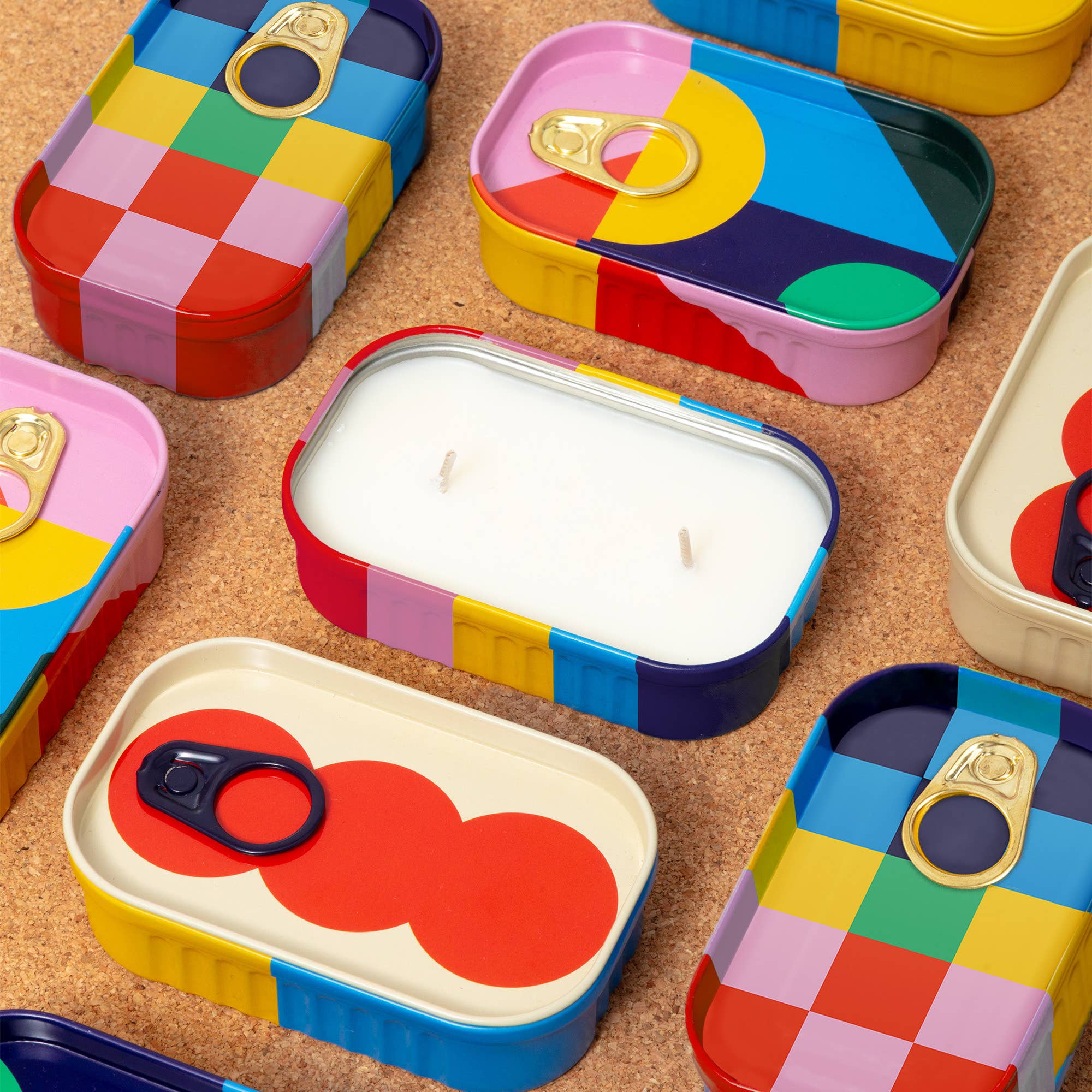 Colorful tin containers with a candle on a textured surface