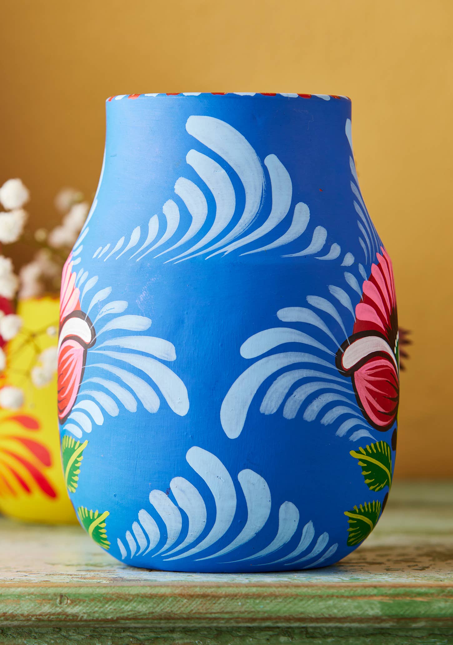 Blue vase with colorful abstract design on a wooden surface