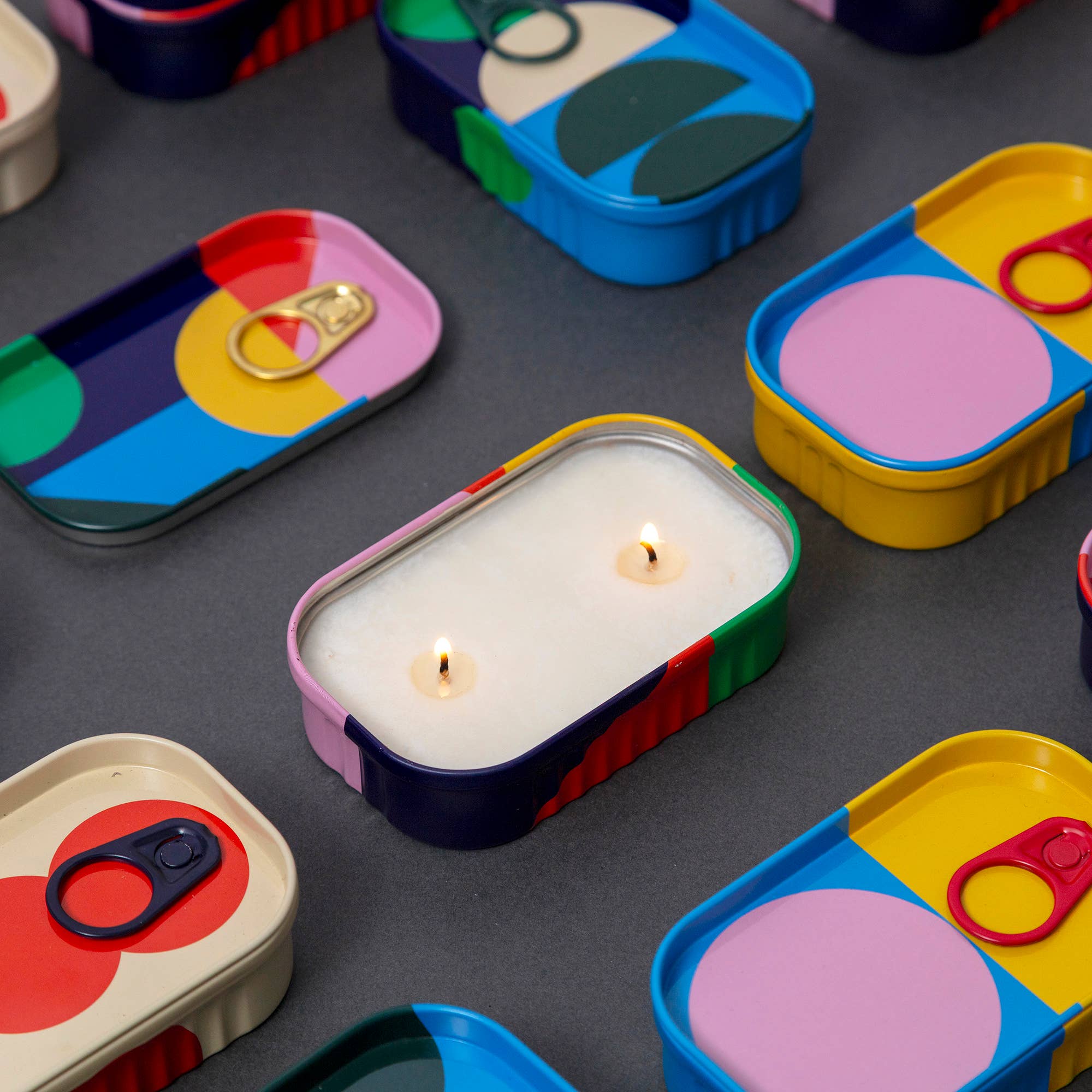 Colorful containers with candles on a dark surface