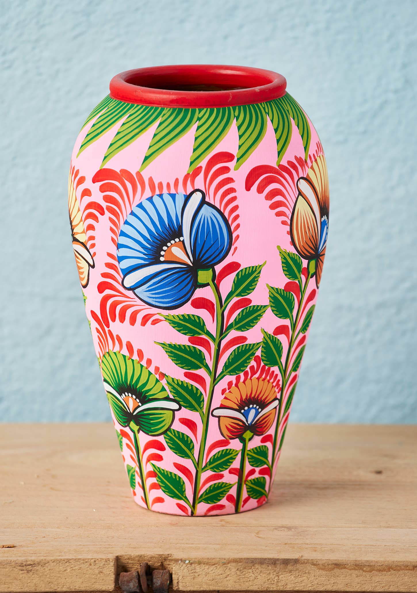 Colorful hand-painted vase with floral and floral design on a wooden surface.