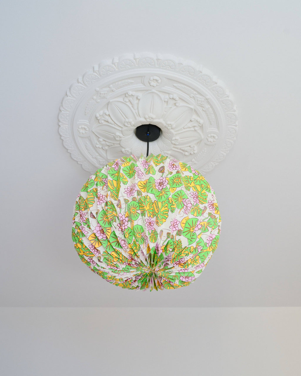 Decorative ceiling light fixture with floral pattern on a white ceiling