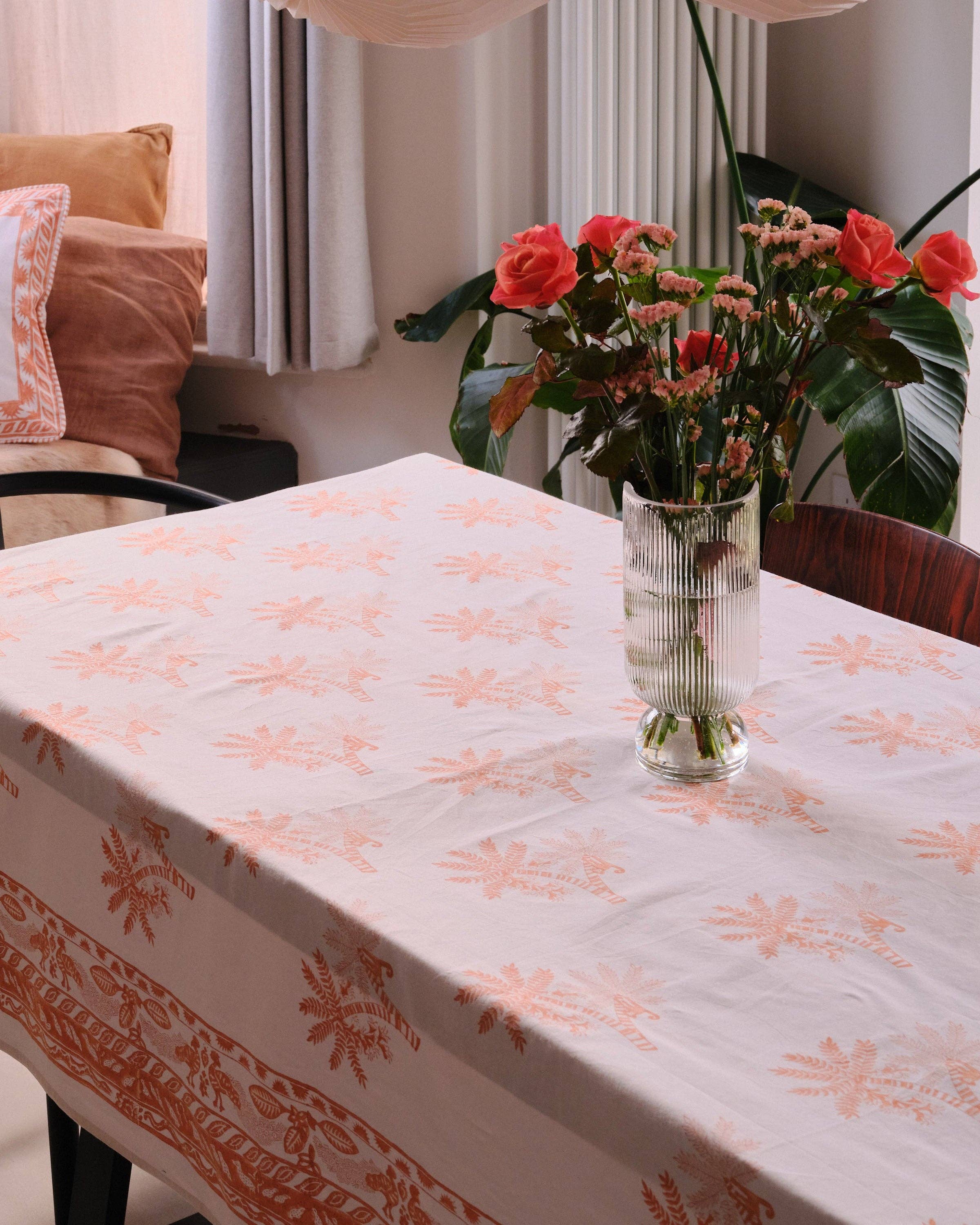 Dining table with a floral-patterned tablecloth and a vase of flowers.