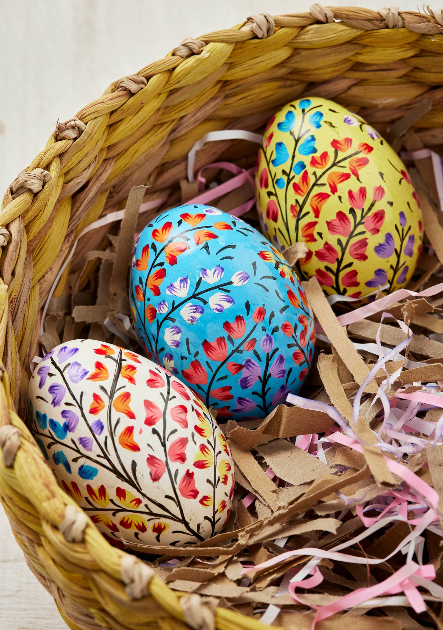 Colorful Easter eggs with floral patterns in a woven basket.