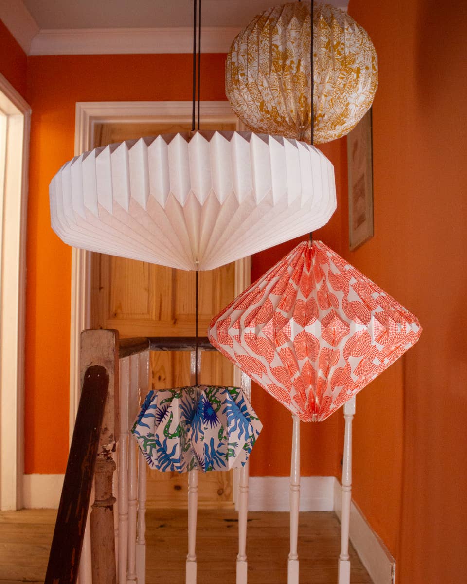 Decorative paper lanterns hanging in a room with orange walls.