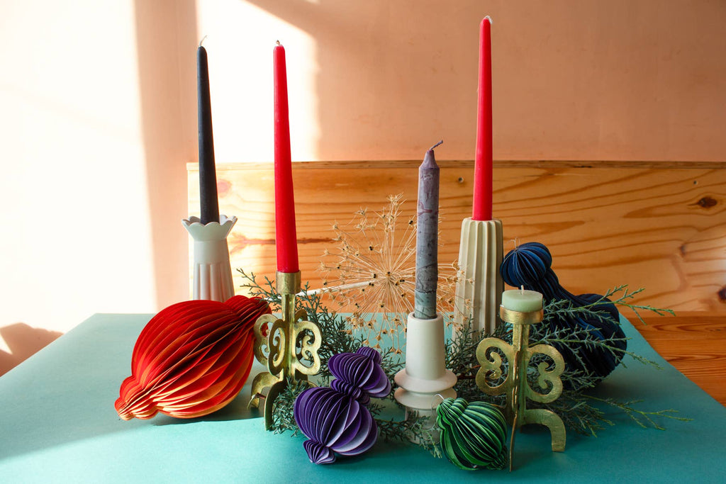 Decorative candles and candle holders on a table with a wooden wall background