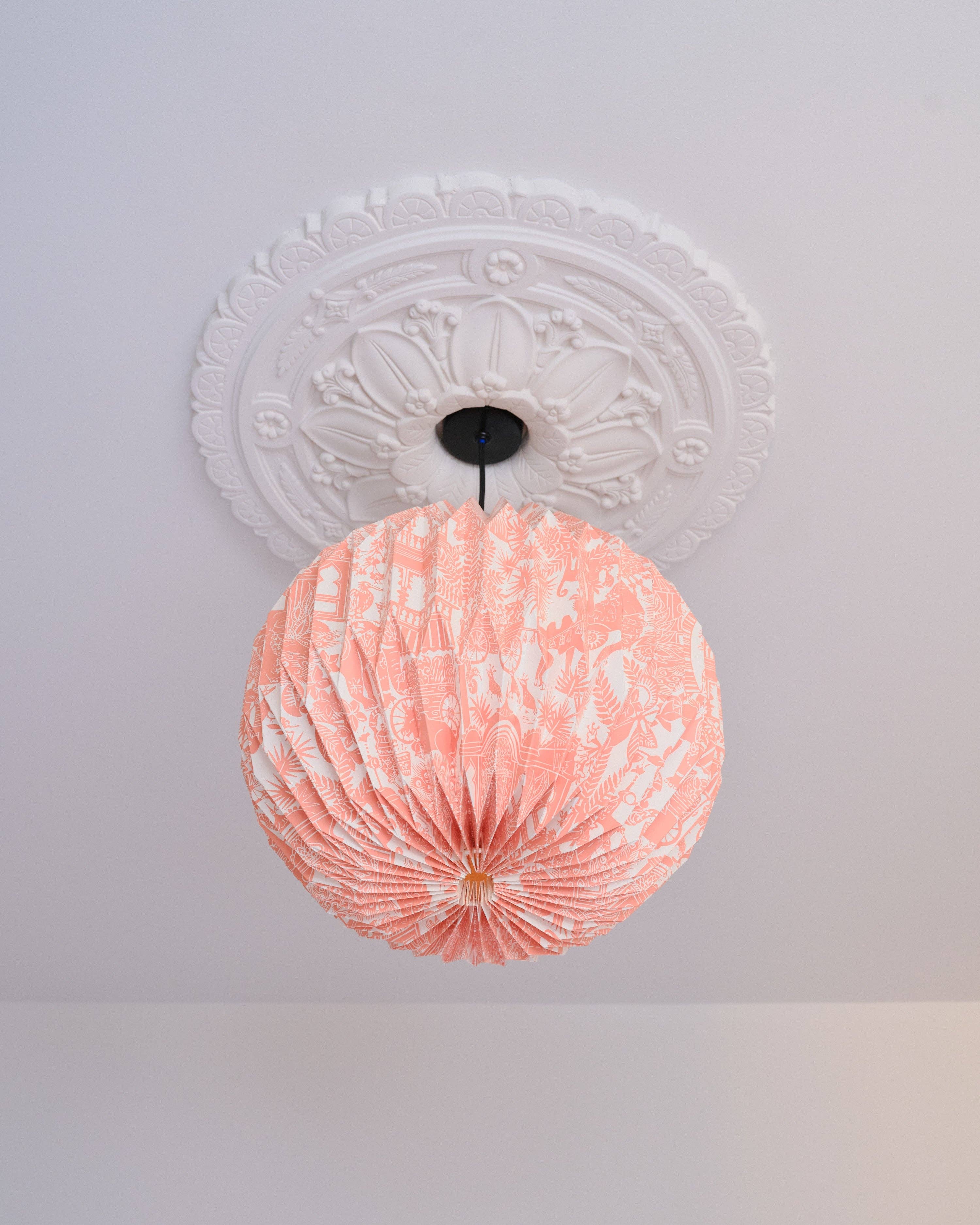 Pink ceiling light fixture on a white ceiling with decorative molding