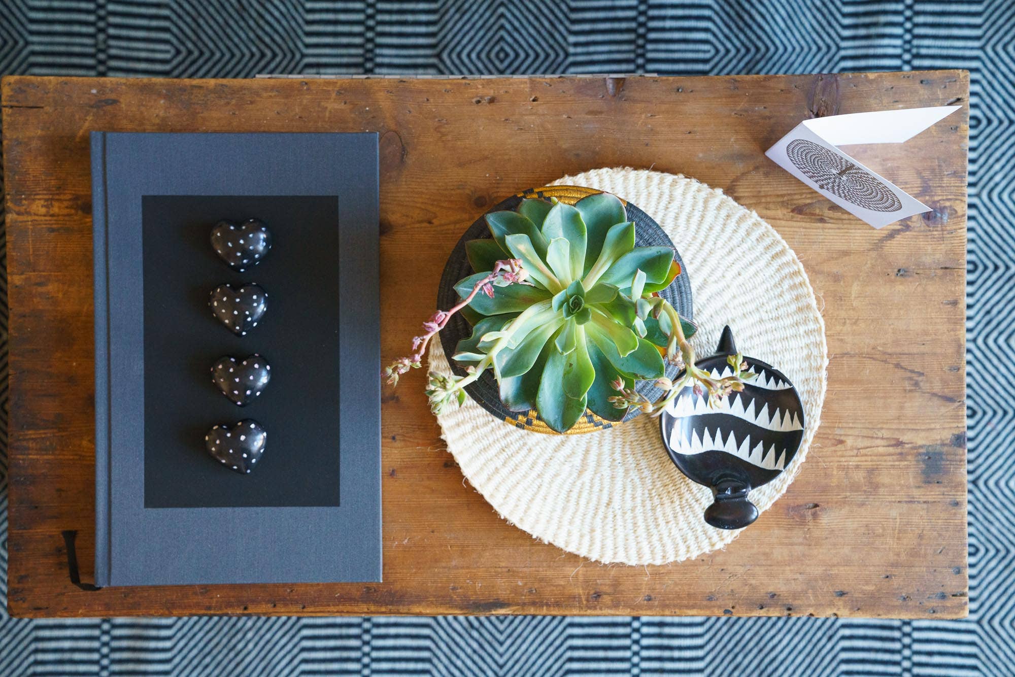 Decorative items including a black book, succulent plant, and decorative plate on a wooden table.