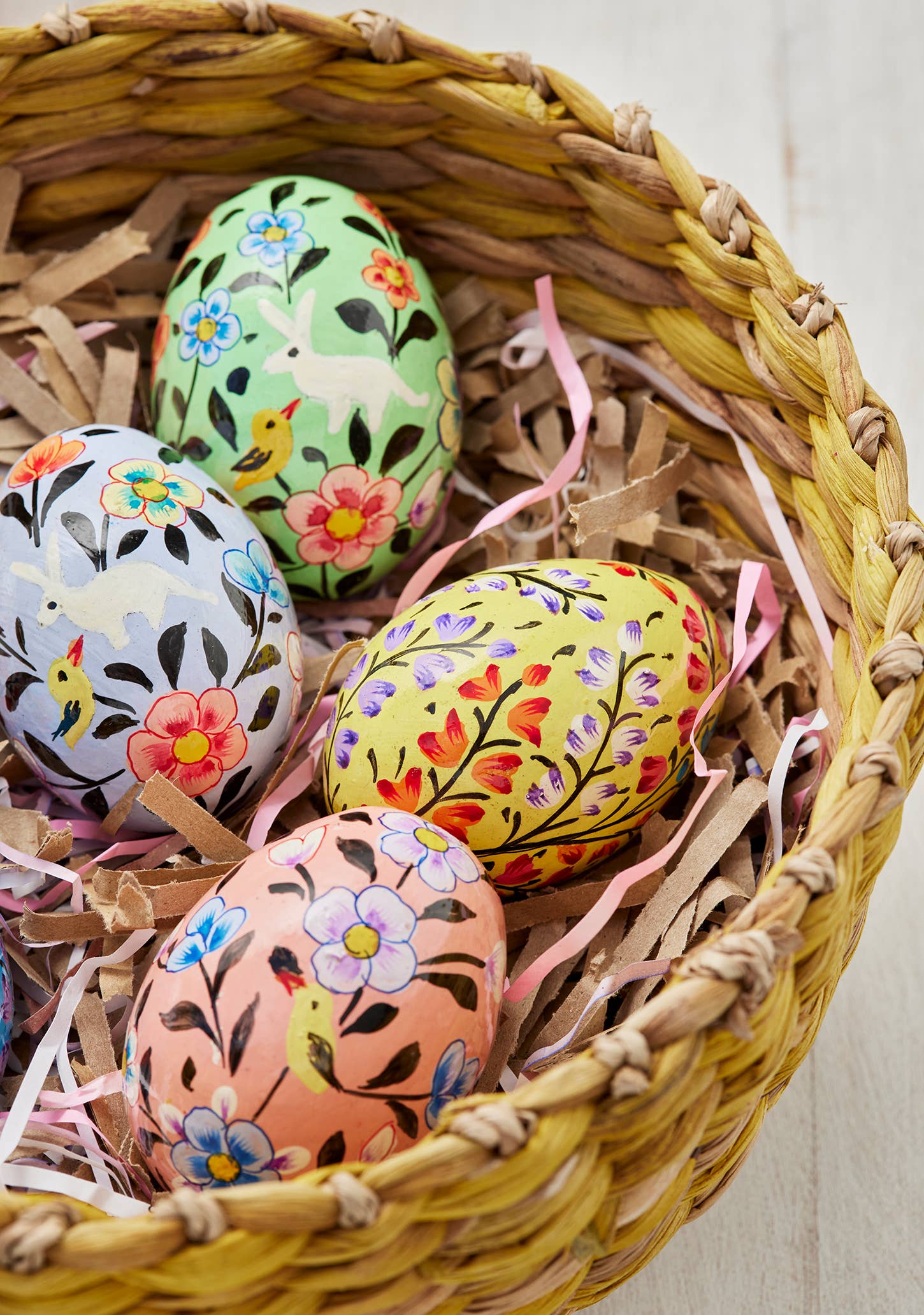 Decorative Easter eggs with floral patterns in a woven basket.