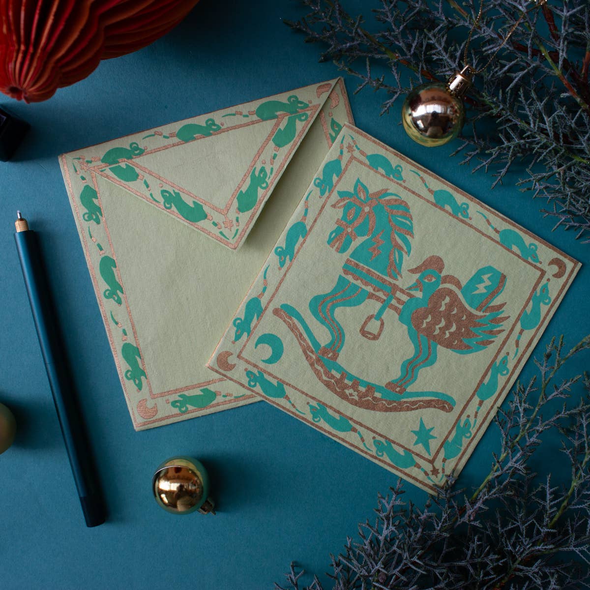 Decorative card with a horse and carriage design on a blue surface with decorative elements.