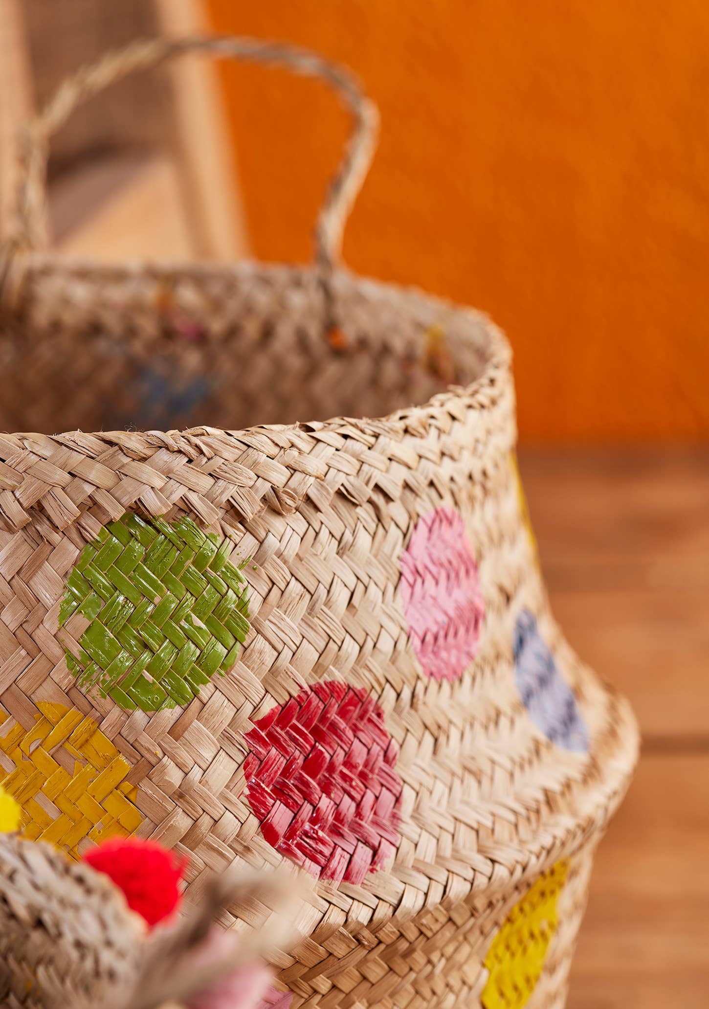 Woven basket with colorful painted designs on a wooden surface