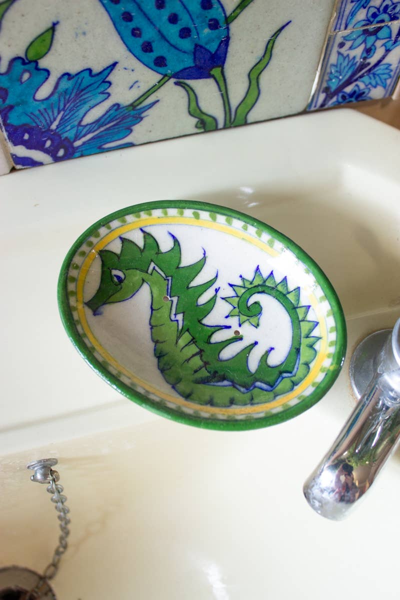 Decorative ceramic plate with a green seahorse design on a sink