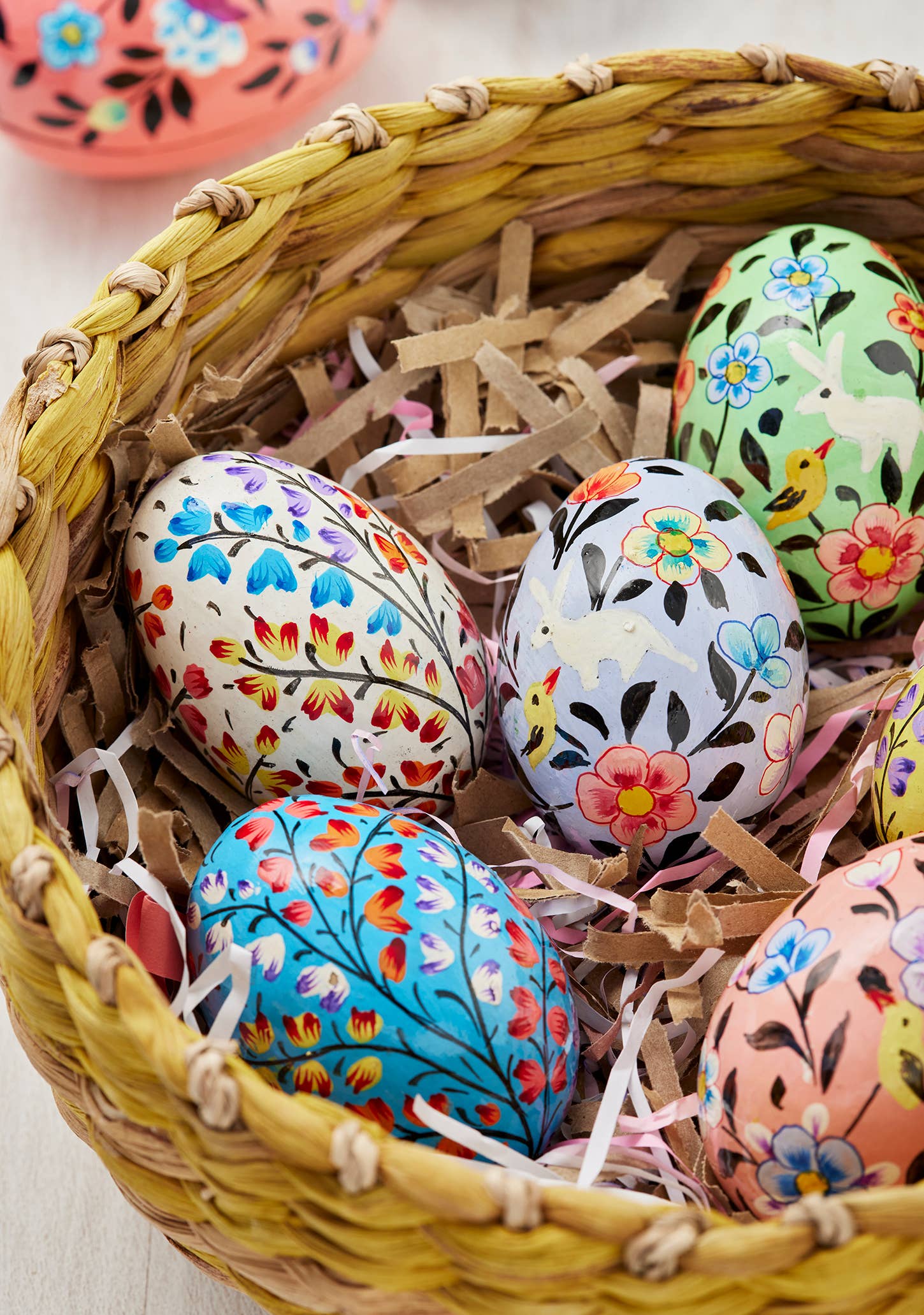 Decorative Easter eggs with floral patterns in a woven basket.