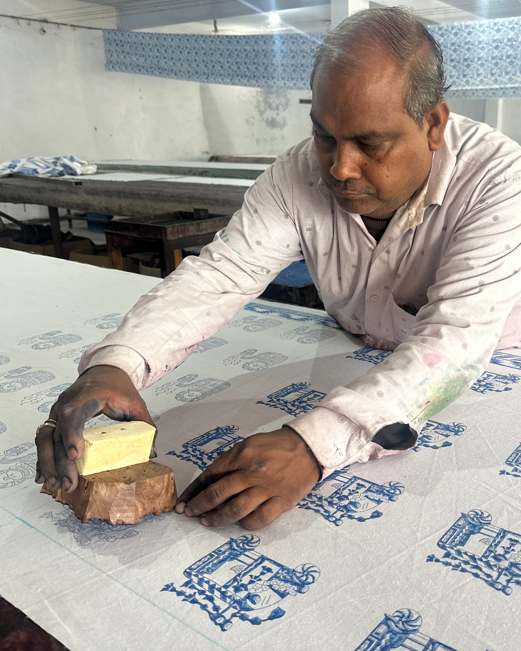 Man hand printing a design onto a table cloth using a wooden block