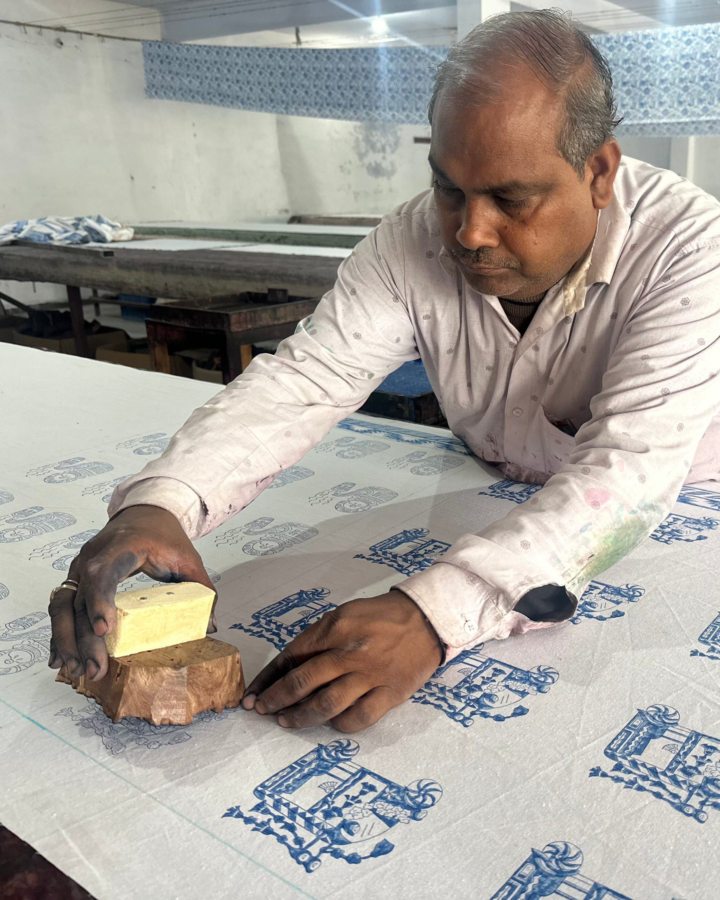 Man hand printing a design onto a table cloth using a wooden block