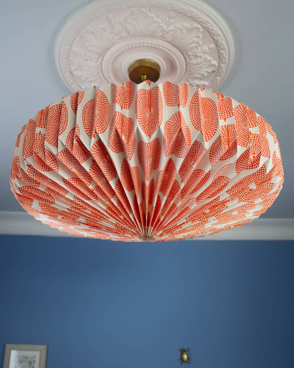Decorative ceiling light fixture with a coral and white pattern on a blue wall.