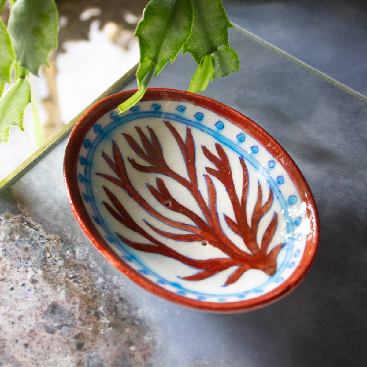 Ceramic bowl with leaf design on a textured surface