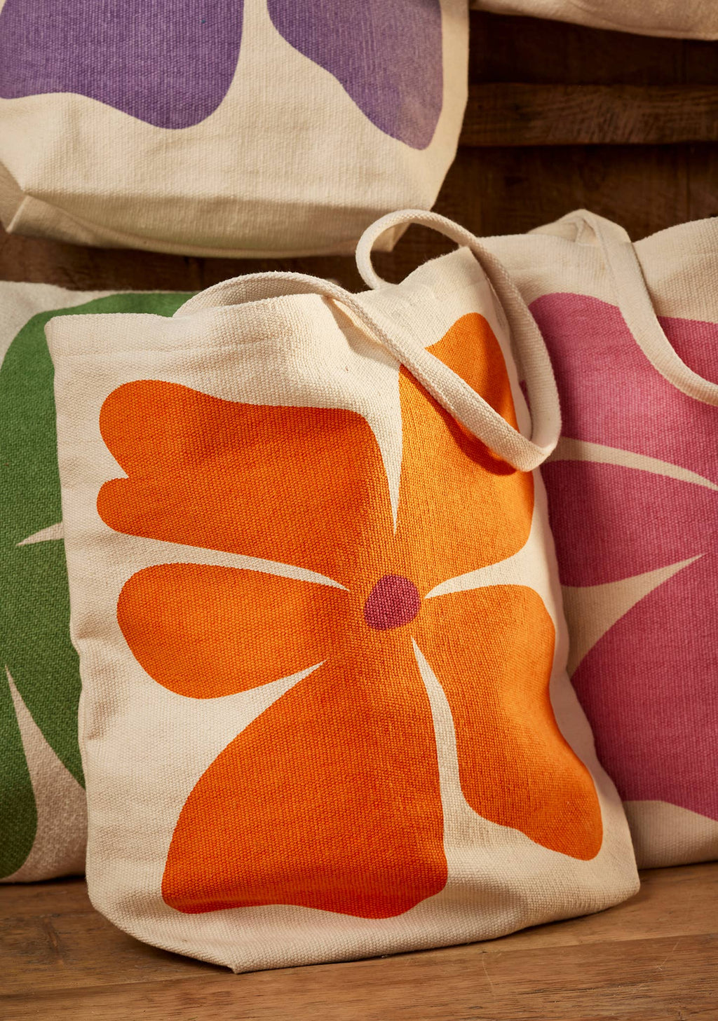 Tote bags with floral designs on a wooden surface