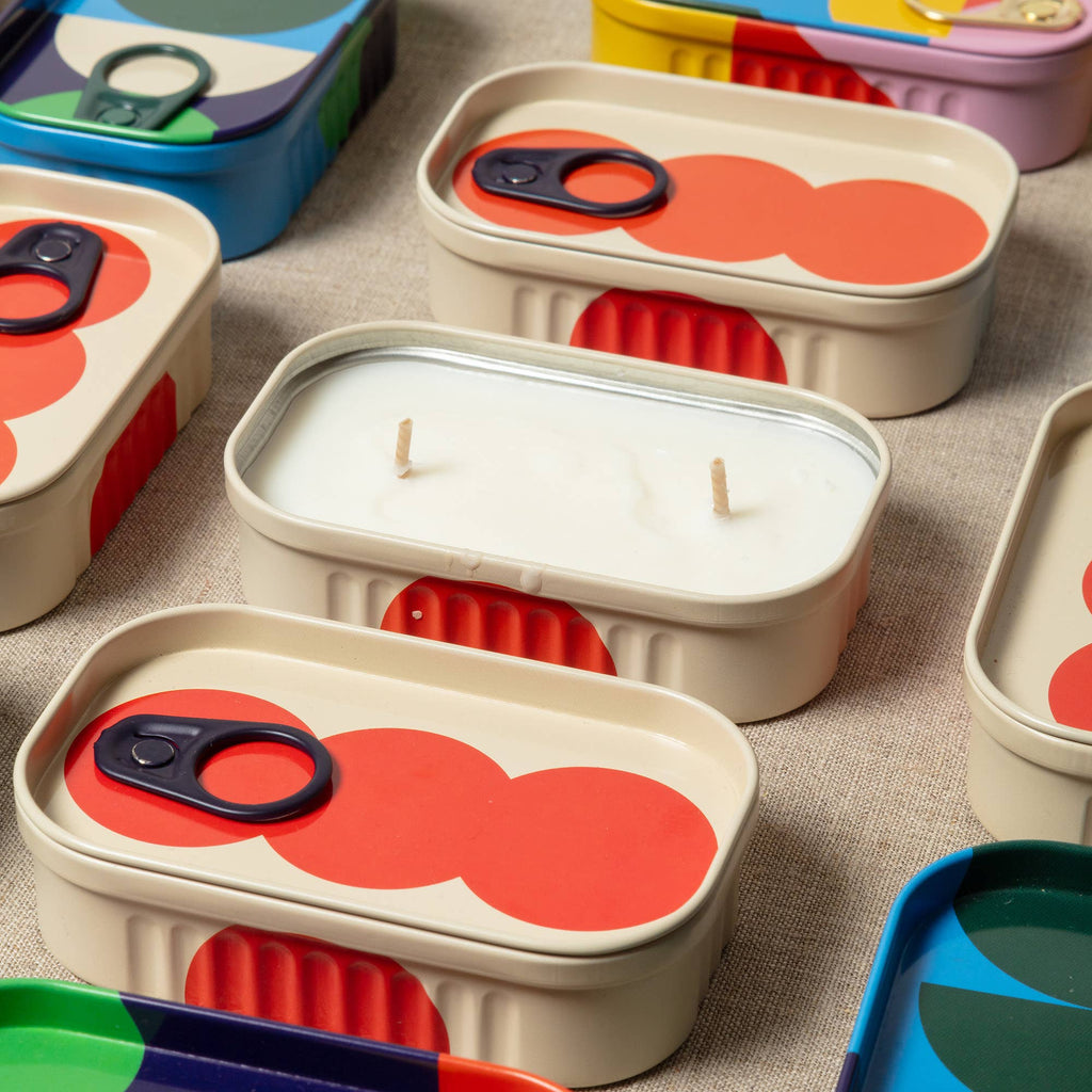 Set of colorful containers with red circular designs on lids, placed on a textured surface.