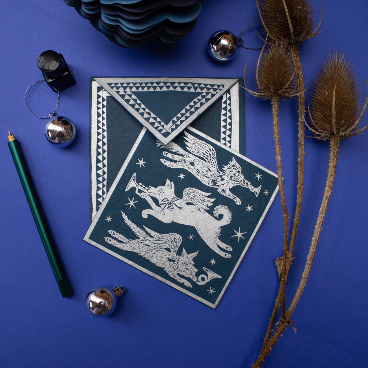 Decorative card with winged creature design on a blue background with decorative elements.