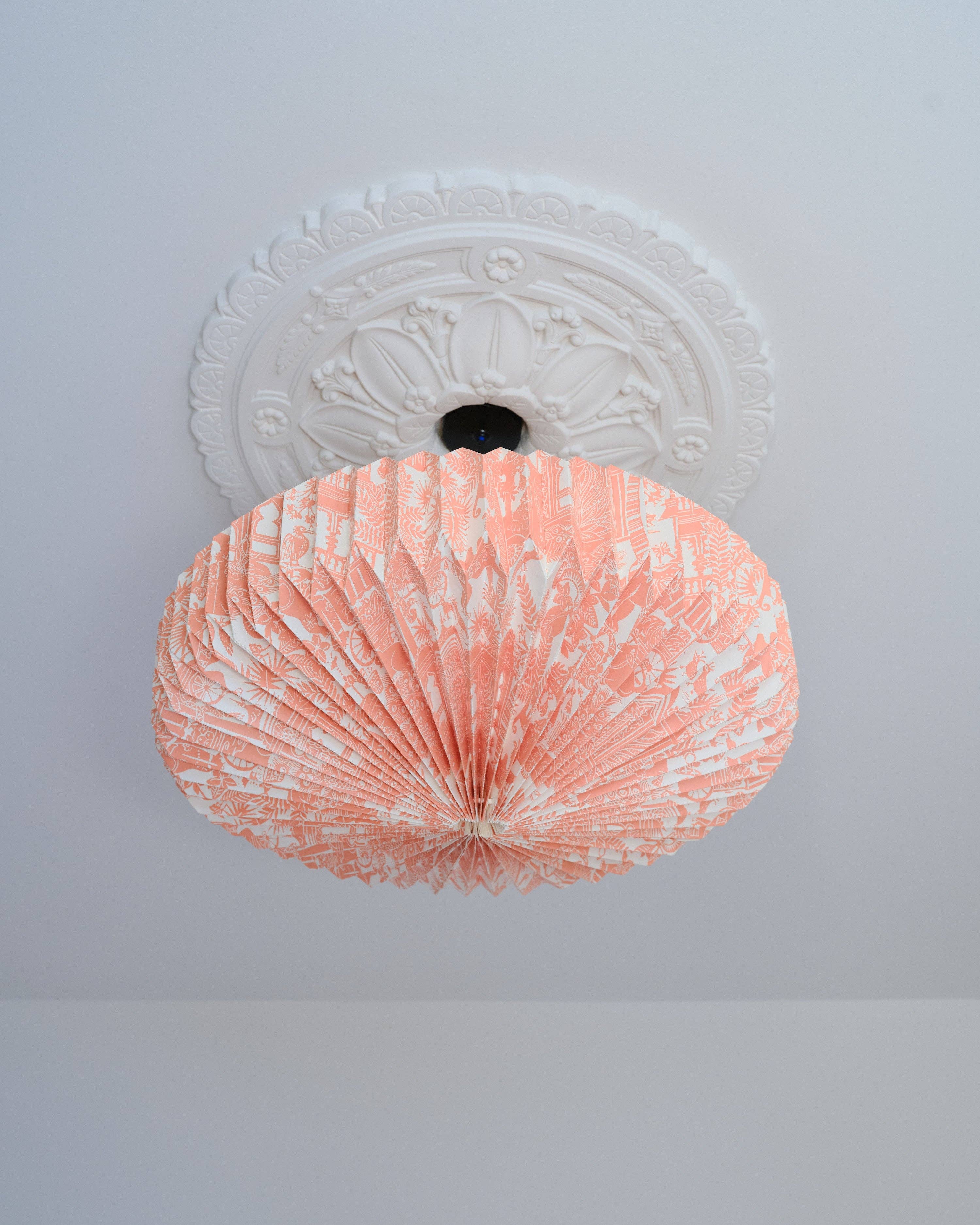 Decorative ceiling light fixture with a pink and white pattern on a plain ceiling.