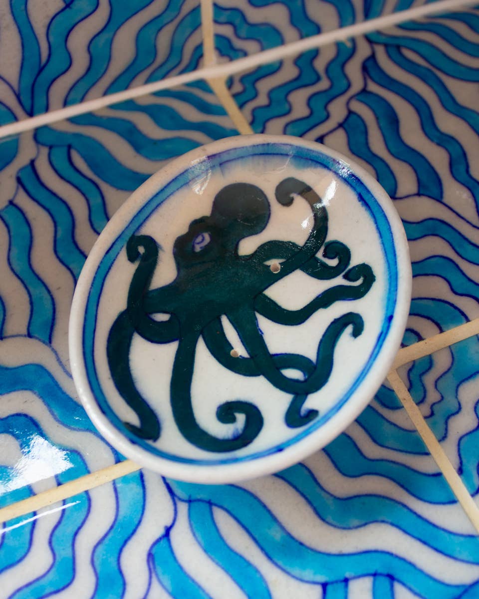 Decorative plate with an octopus design on a blue and white wavy patterned background