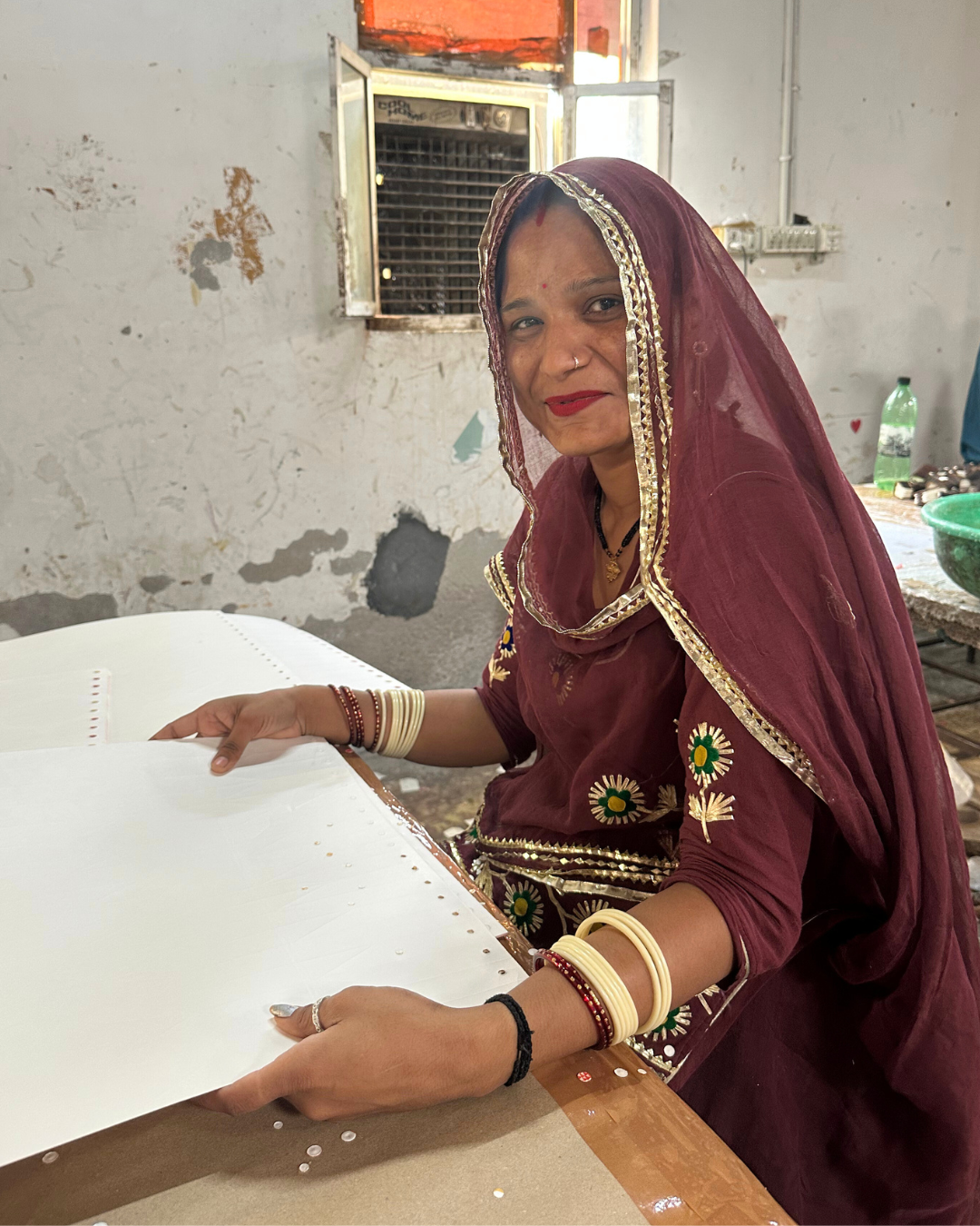 Woman in traditional attire working at a table in an indoor setting