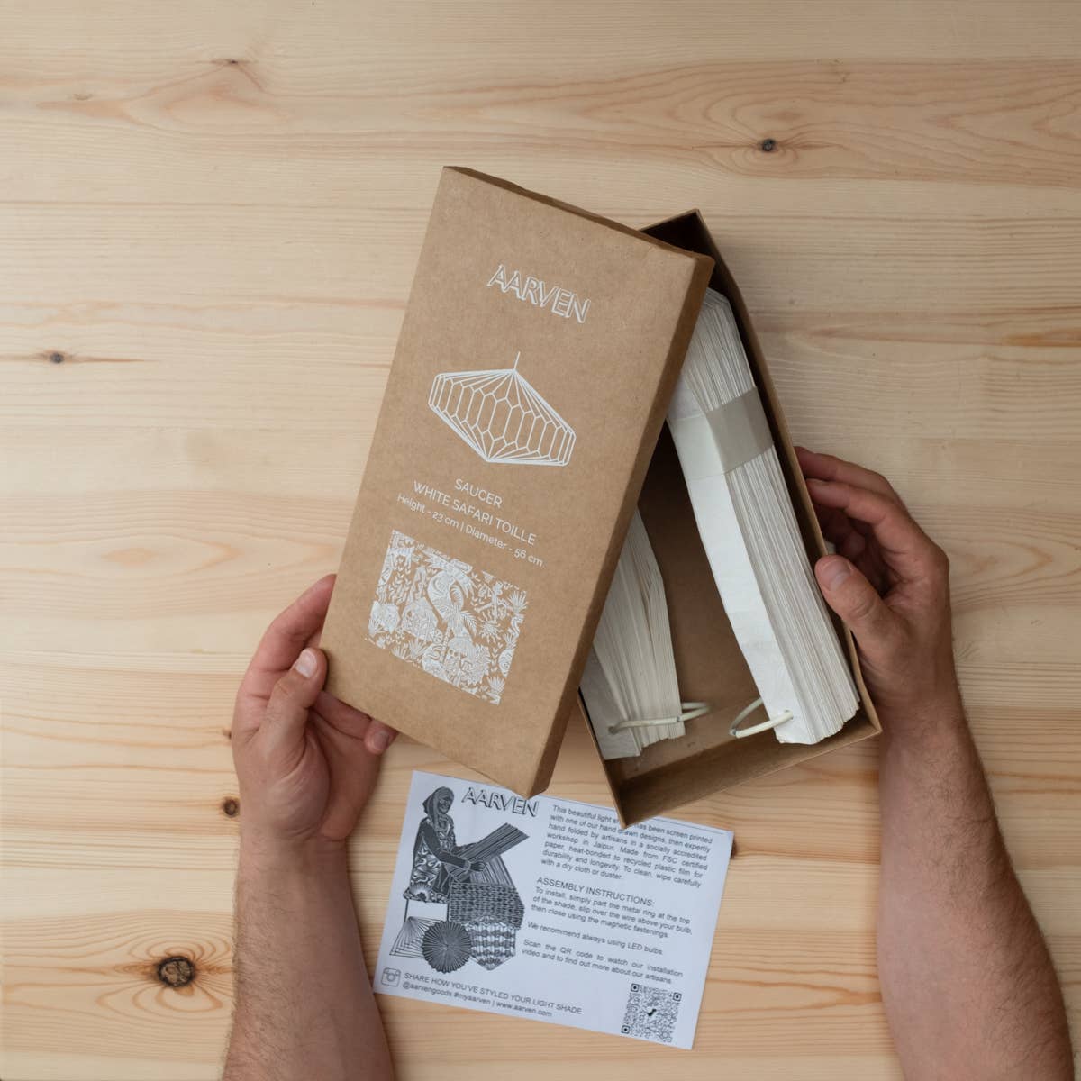 Person holding a cardboard box with white foldable light fixture from Aarven