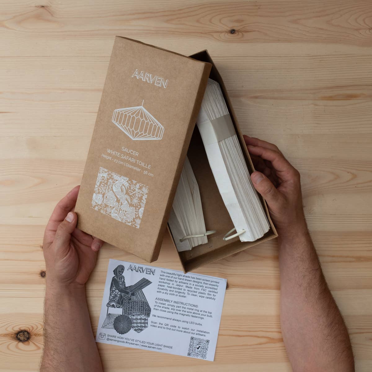 Person holding a brown package with white text and images on a wooden surface