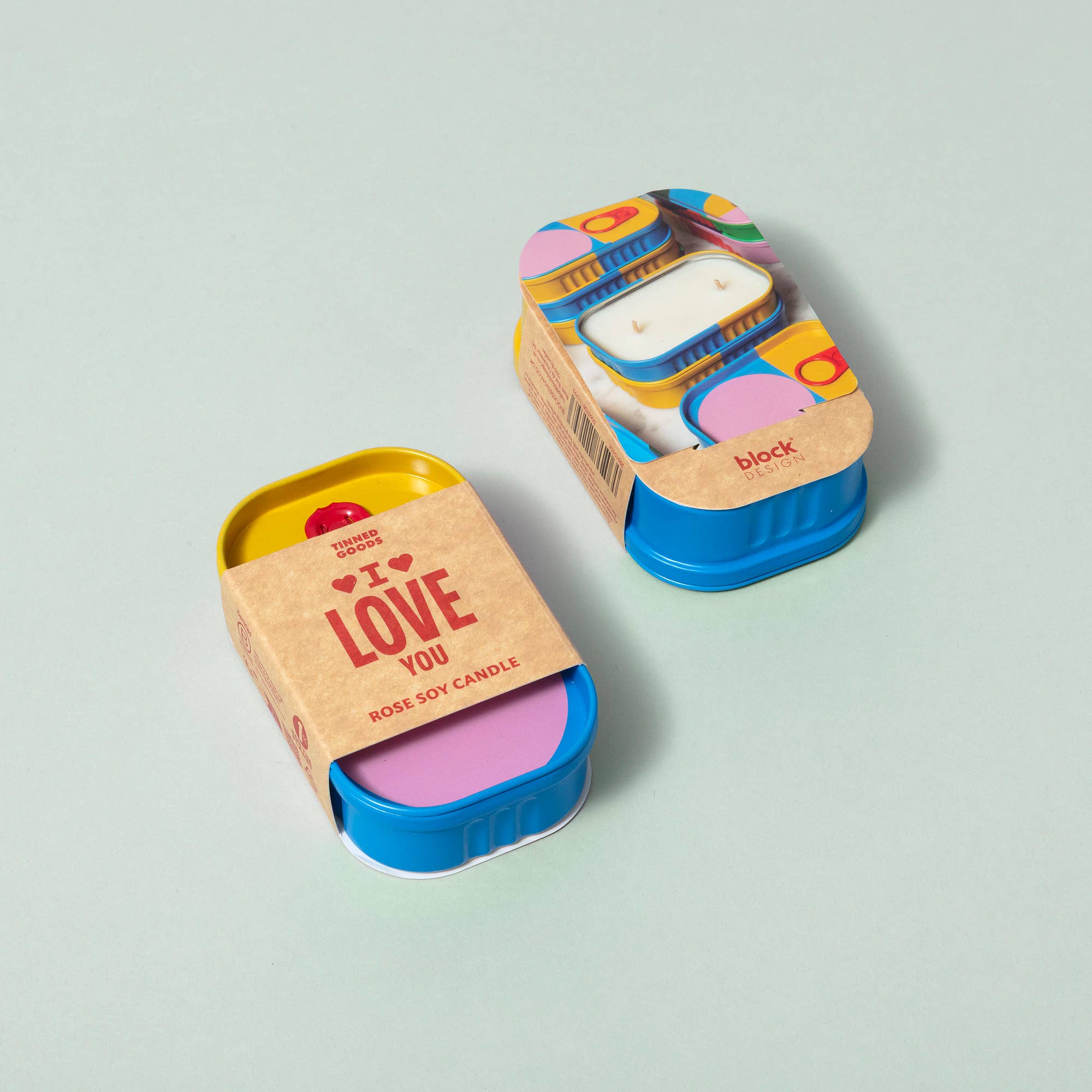 Two small candles in colorful tins on a light green background